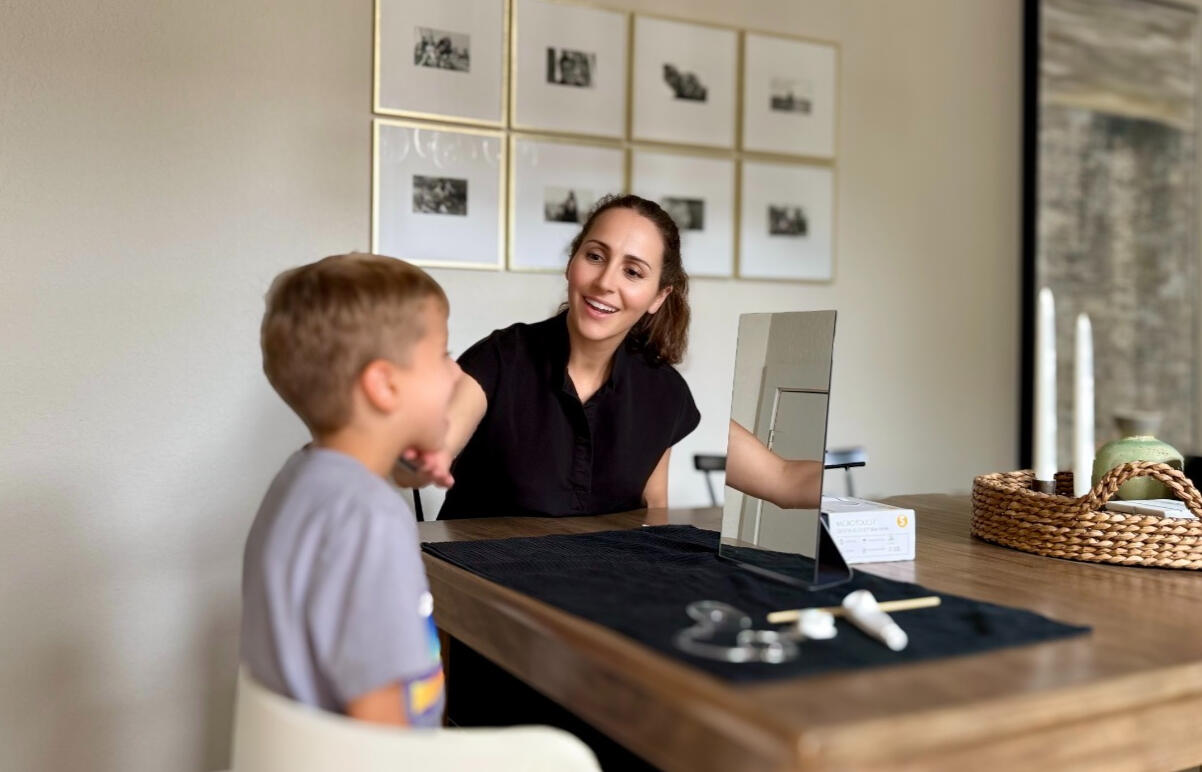 Myofunctional therapist Nancy Groeniger at a table working with a young patient during an in-home myofunctional therapy session.